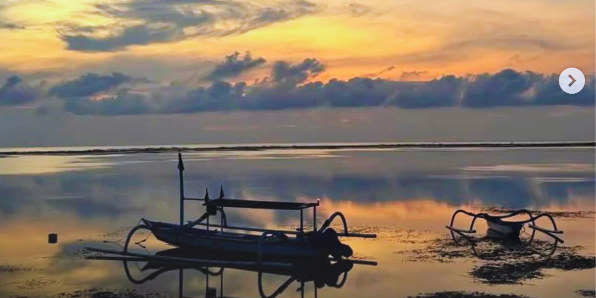 Sunrise in Sanur With Gorgeous oranges, blues and purples and a little boat floating on the calm sea