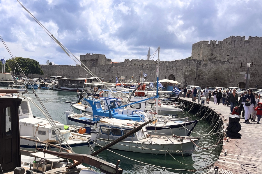 Boats bobbing up and down at Rhodes Town harbour with the city walls in the backkground